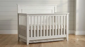 A high-resolution photorealistic view of the complete farmhouse 4-in-1 crib, showcasing its full slatted structure, distressed wood finish, and solid headboard panel.