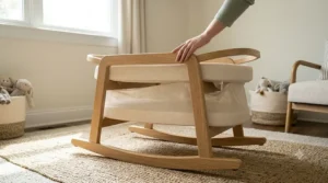 A parent demonstrating the folding frame feature of a modern rocking bassinet with stand.
