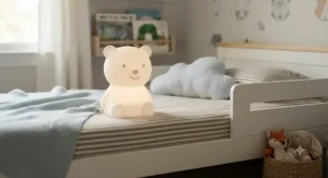 Cute silicone smart LED nursery night light shaped like a bear on a toddler bed